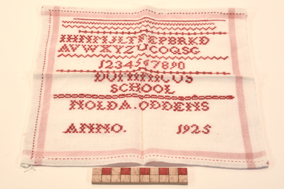 878266 Afbeelding van een merklap met daarop verschillende oefensteken en in rood het alfabet, de cijferreeks 1 t/m o ...